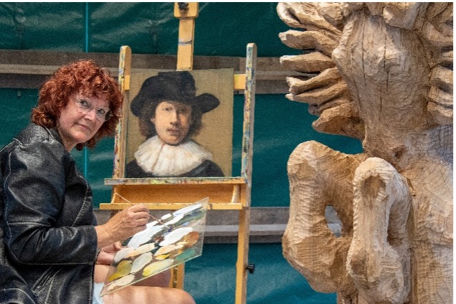 Gepke Hoekstra schildert naast een houten sculptuur
