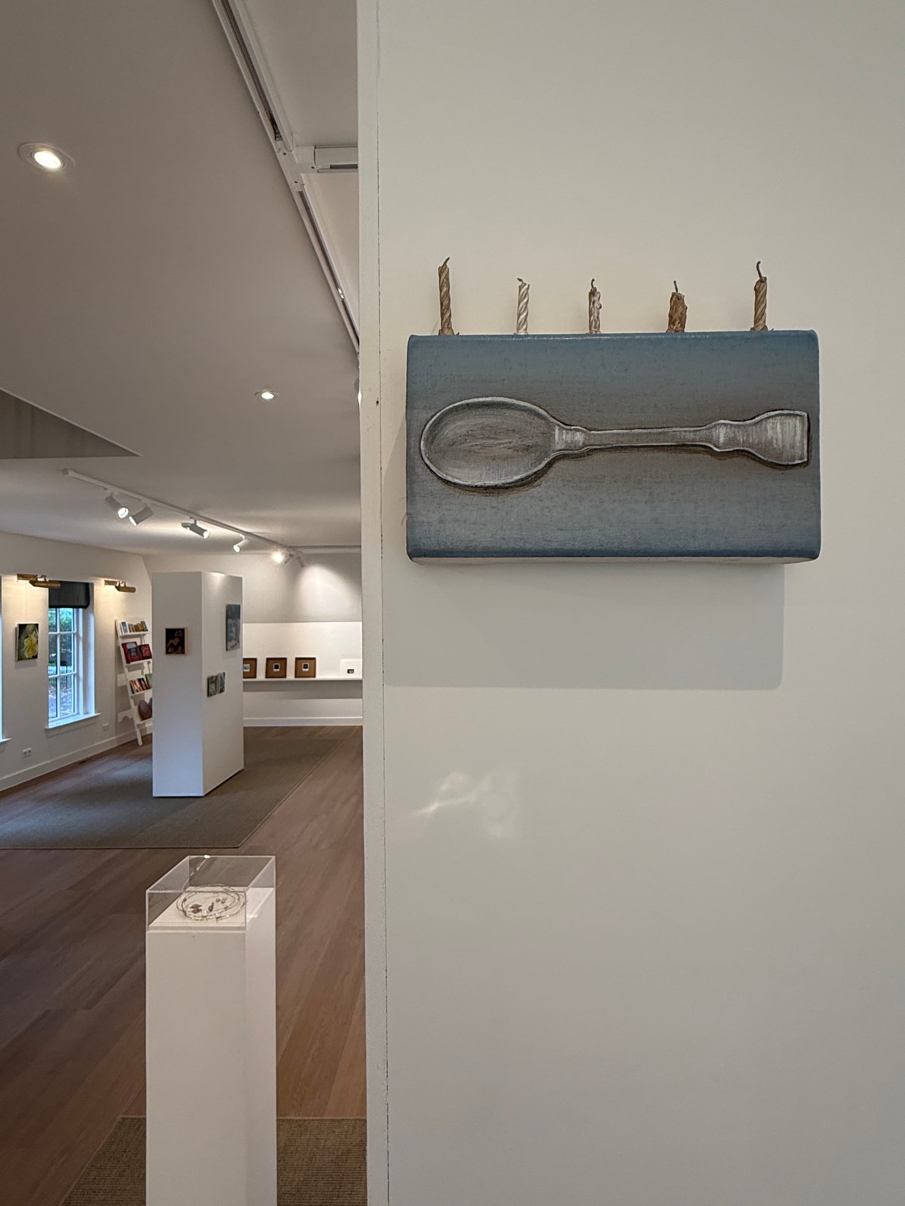 Kunstwerk met een lepel en kaarsen, met de FRIS!-tentoonstelling op de achtergrond
