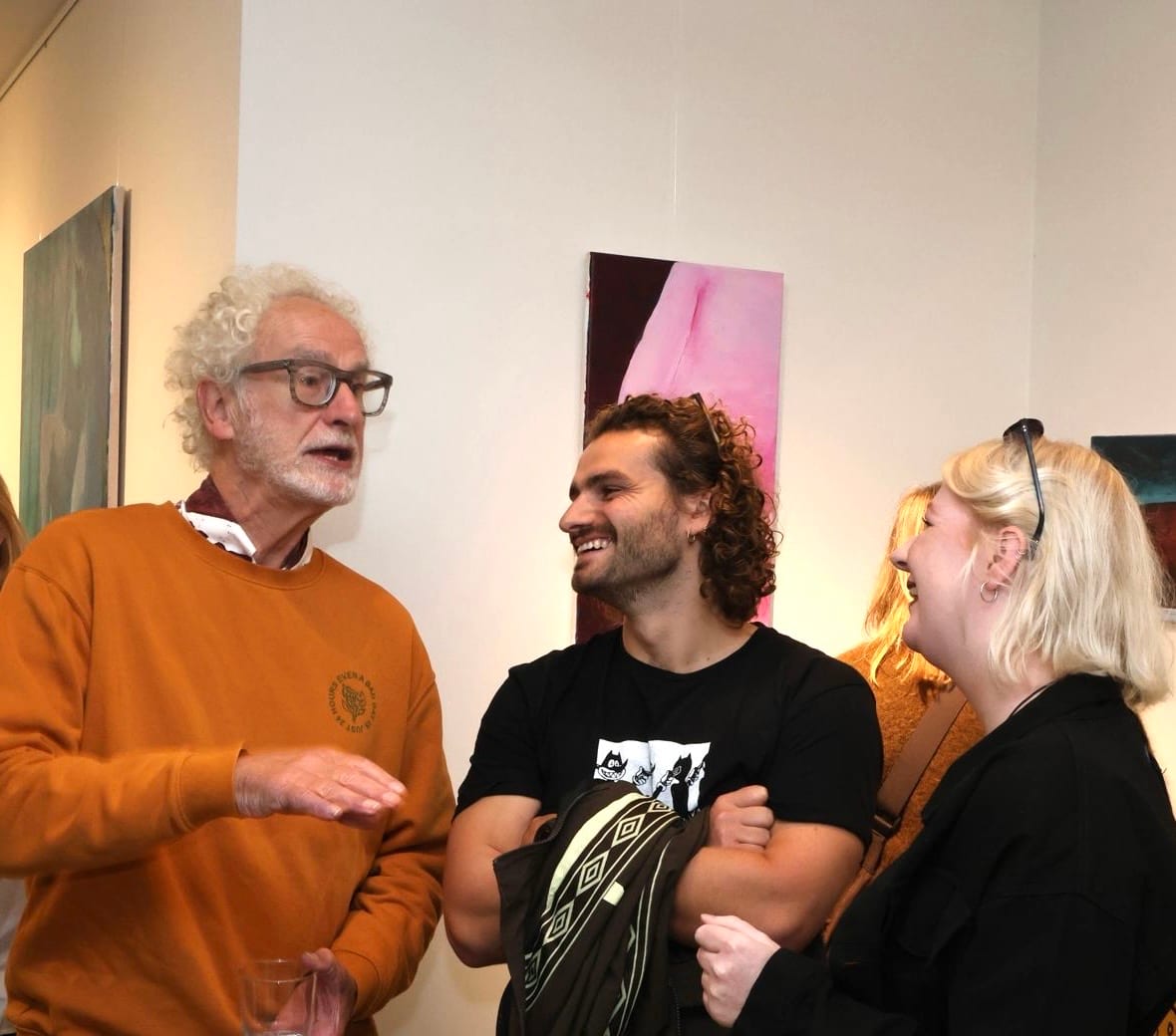 Drie bezoekers in gesprek voor schilderijen tijdens de opening van FRIS!